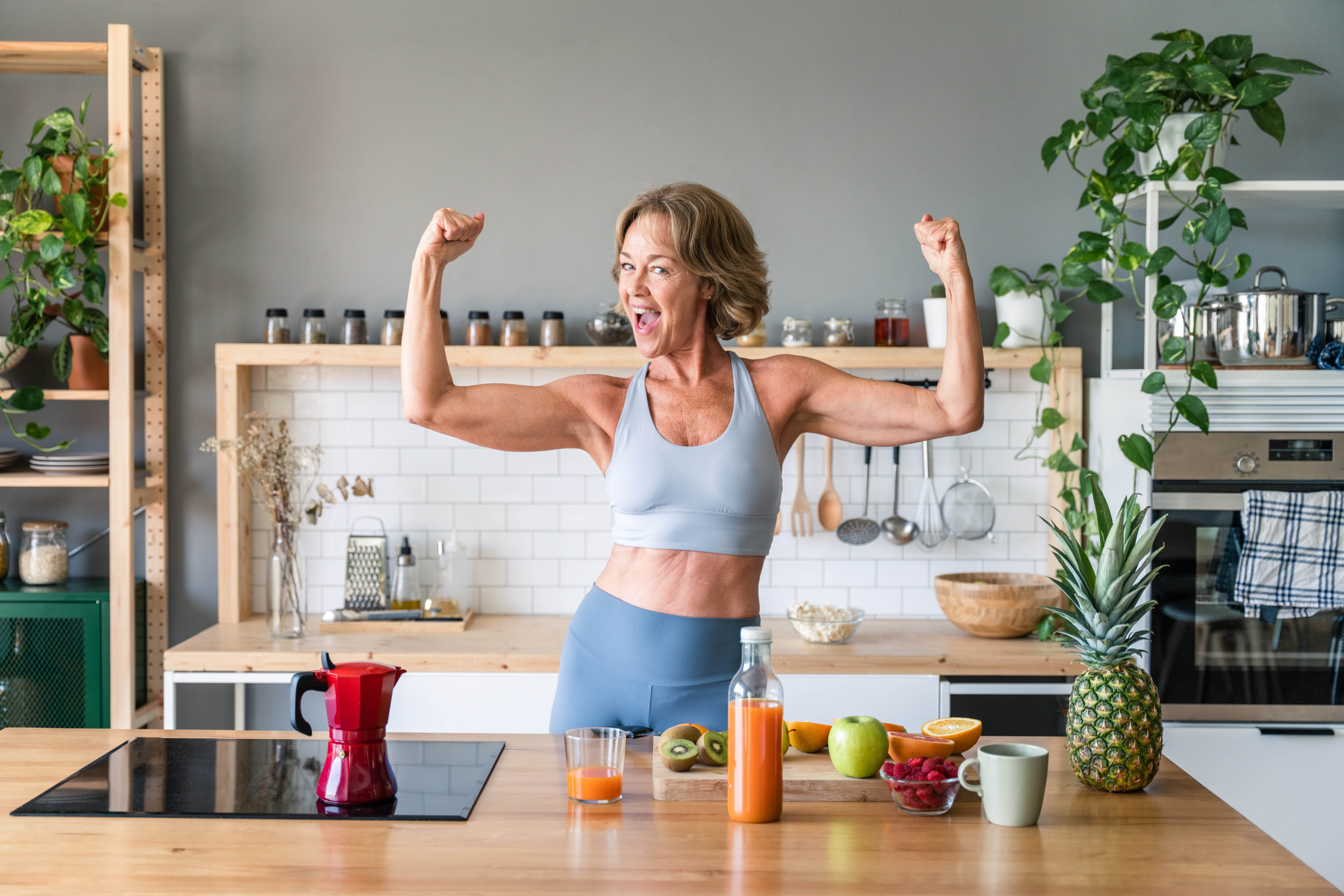Strong woman posing in the kitchen with her arms flexed